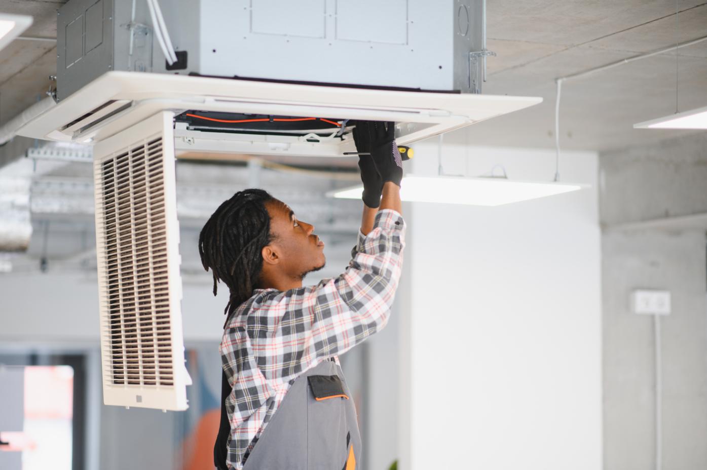 Technician repairing ceiling-mounted air conditioning unit